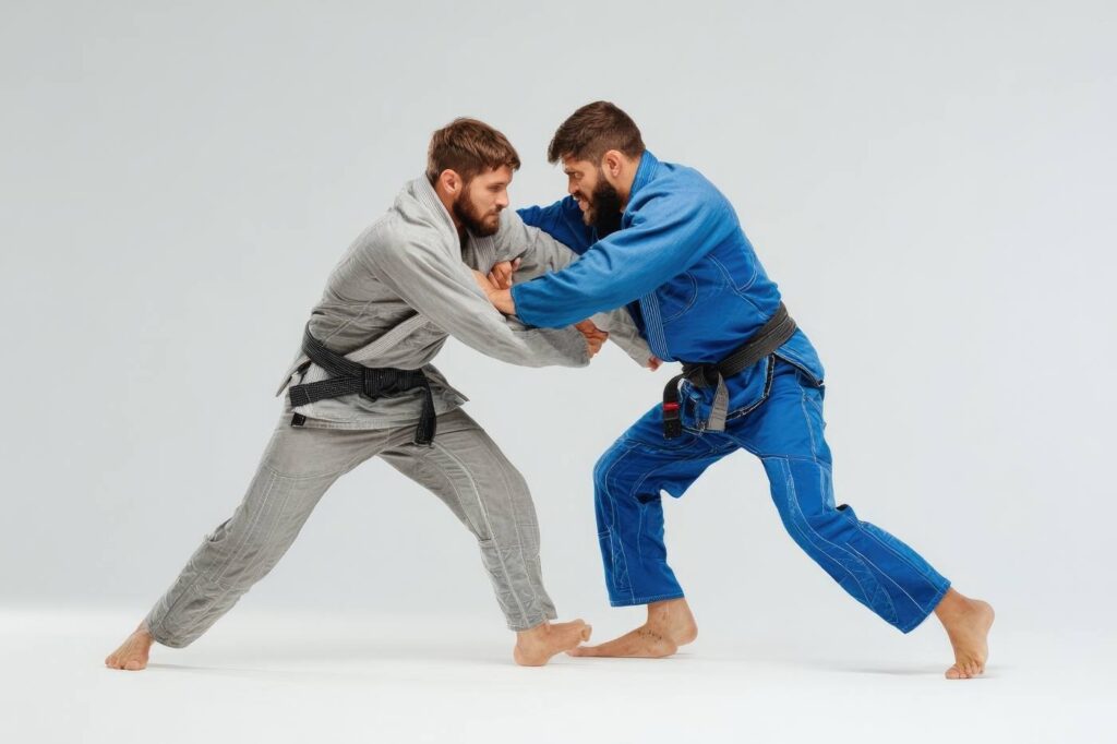 Two martial artists in traditional gi uniforms practising Brazilian Jiu-Jitsu grappling techniques